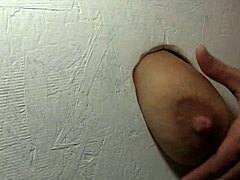 A stunning woman pleasures herself and gives oral pleasure to an unknown partner through a gloryhole