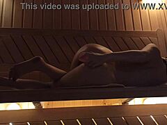 Uma jovem desfruta da sauna com um dildo rosa, experimentando o orgasmo